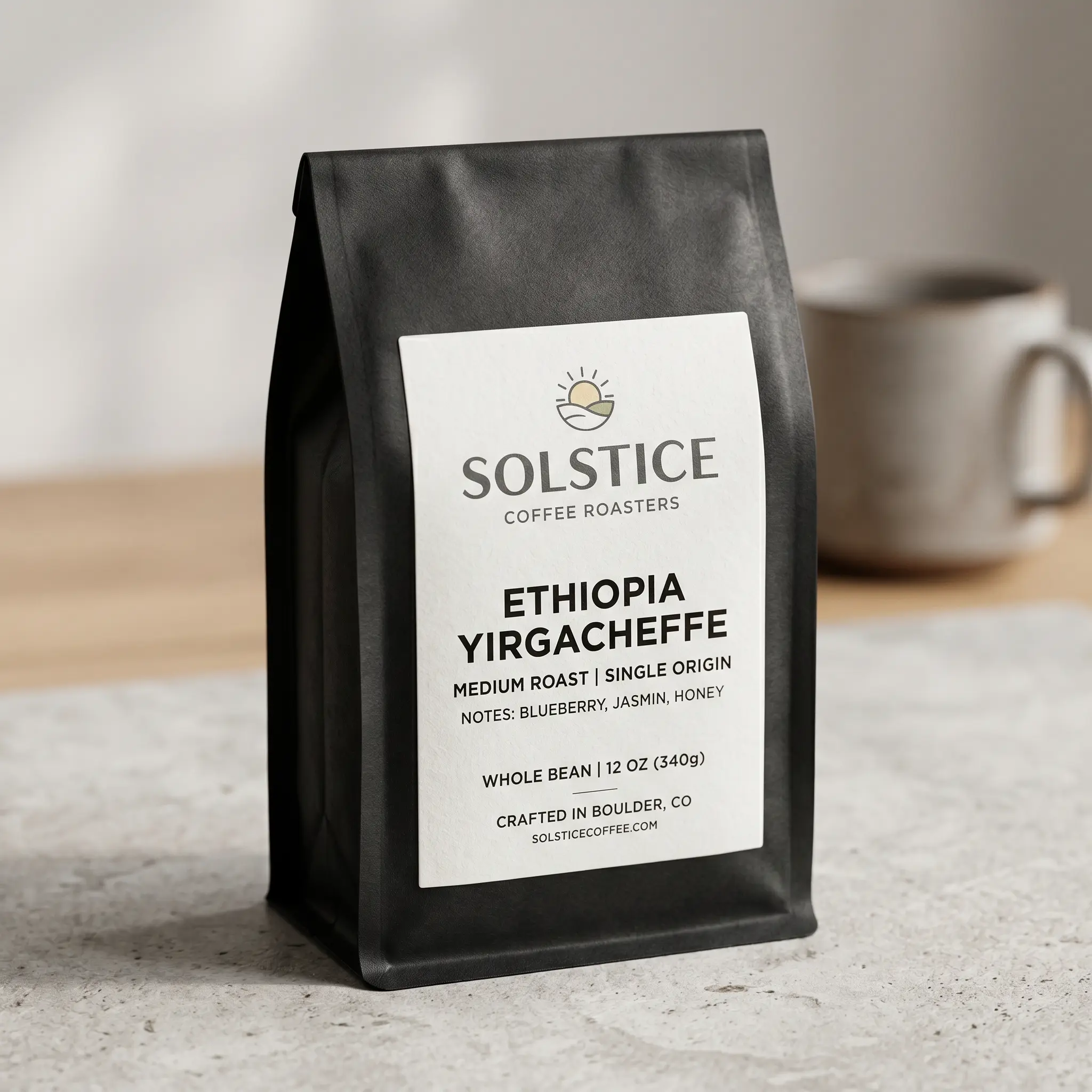 Black coffee bag packaging for Solstice Coffee Roasters Ethiopia Yirgacheffe on marble counter with coffee cup background