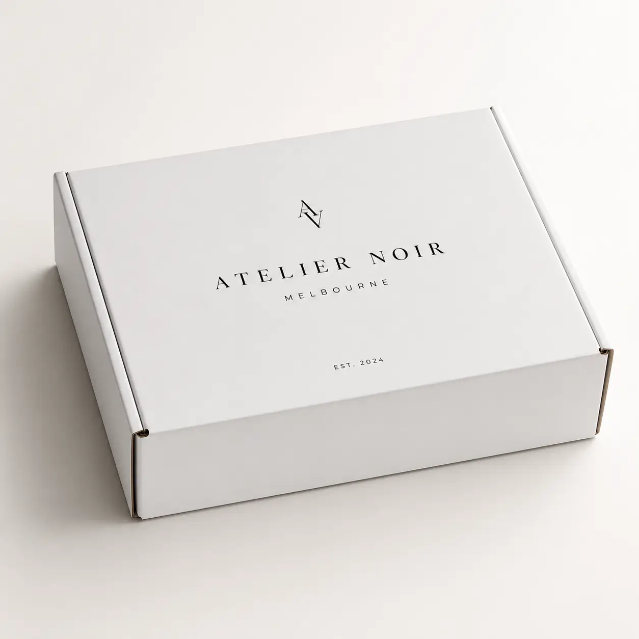 White luxury mailer box printed with Atelier Noir Melbourne logo, minimalist custom packaging design, EST. 2024, clean branding