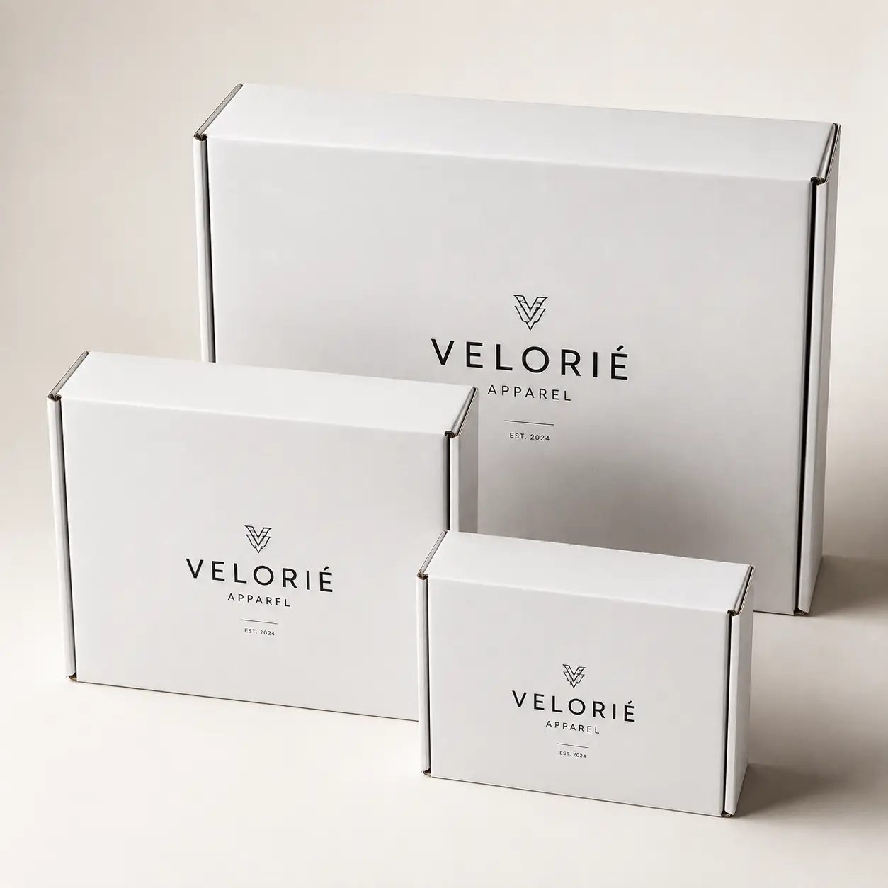 Three white Velorié Apparel custom branded mailer boxes in small, medium, large sizes with minimalist black logo on neutral background