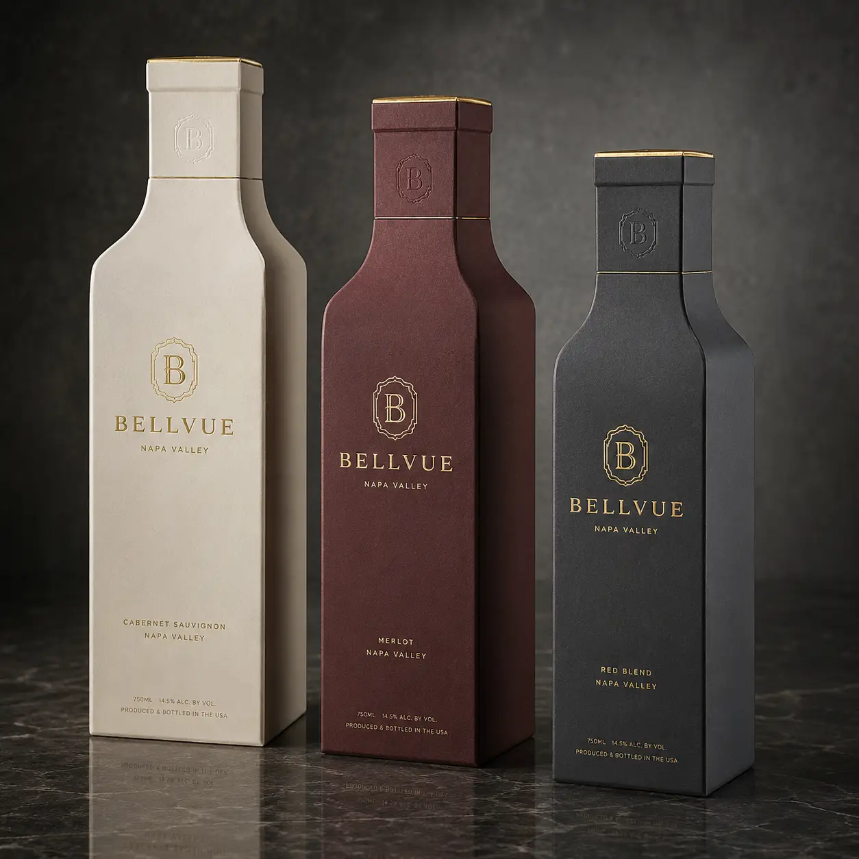 Three Bellvue Napa Valley wine bottle boxes in cream, burgundy, and charcoal with gold foil branding on marble surface
