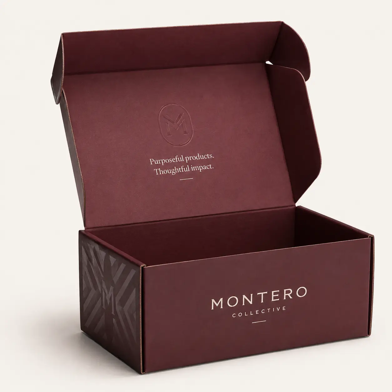 Luxury burgundy mailer box open showing Montero Collective branding, embossed logo, custom printed packaging with geometric pattern
