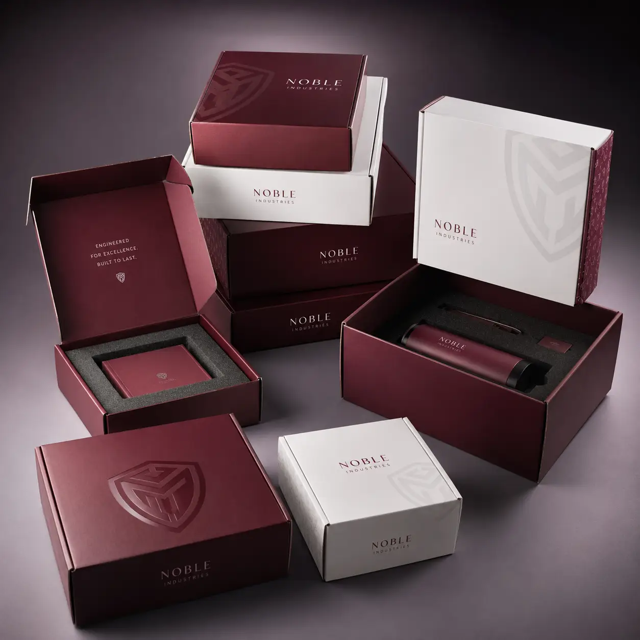 Noble Industries luxury packaging collection featuring deep burgundy and white branded boxes with foam inserts, premium unboxing experience