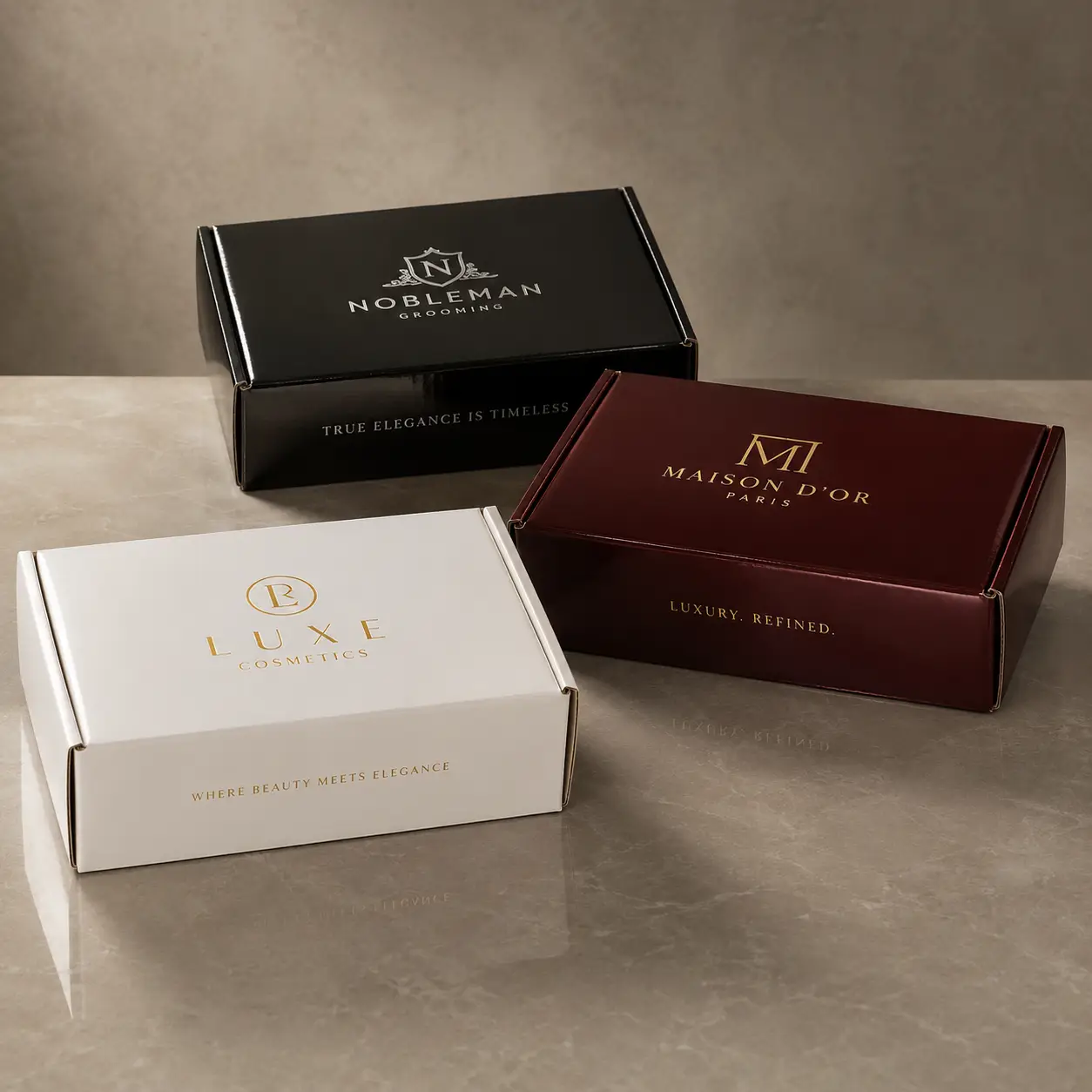 Three luxury custom printed mailer boxes in black, white, and burgundy displaying premium brand logos on marble surface