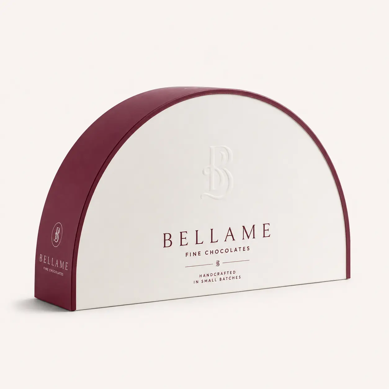 Bellame Fine Chocolates semicircular luxury gift box, cream white with embossed logo, deep burgundy trim, handcrafted small batch packaging