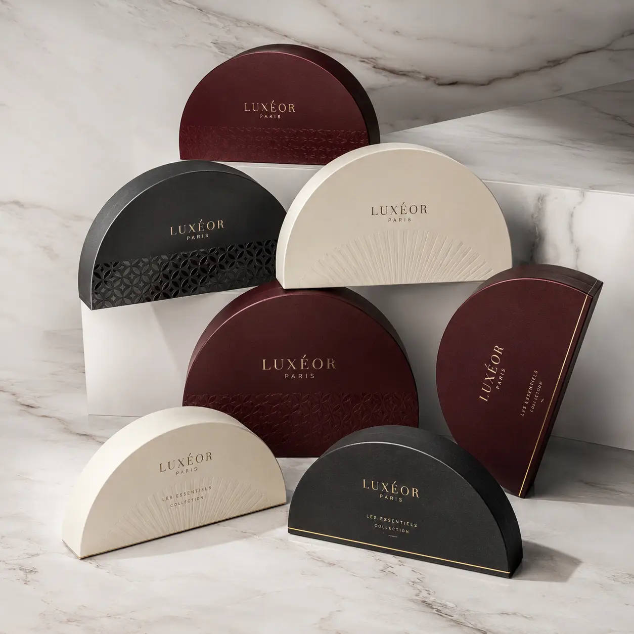 Luxéor Paris luxury gift boxes in burgundy, black, and cream semicircle shapes displayed on marble surface