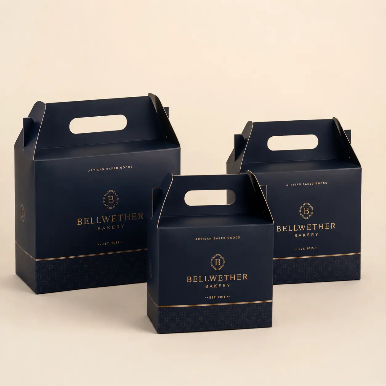 Three navy blue gable bakery boxes with gold Bellwether Bakery branding, artisan baked goods packaging in graduated sizes
