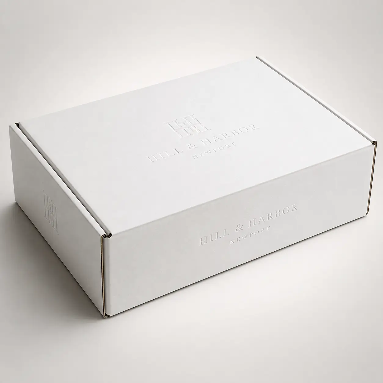 White embossed corrugated mailer box with Hill & Harbor Newport logo, minimalist luxury custom packaging design