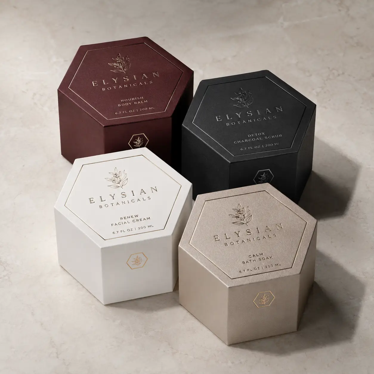 Four luxury hexagonal Elysian Botanicals skincare boxes in burgundy, black, white, and taupe with gold embossed botanical branding