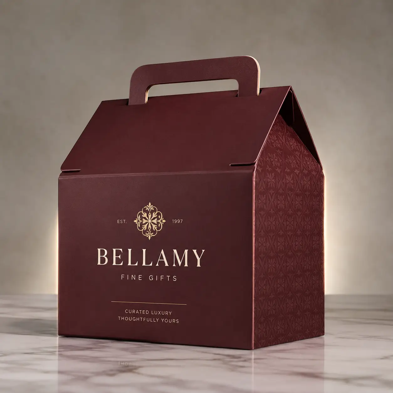 Luxury burgundy gable gift box with gold foil Bellamy Fine Gifts branding on marble surface, premium custom packaging design