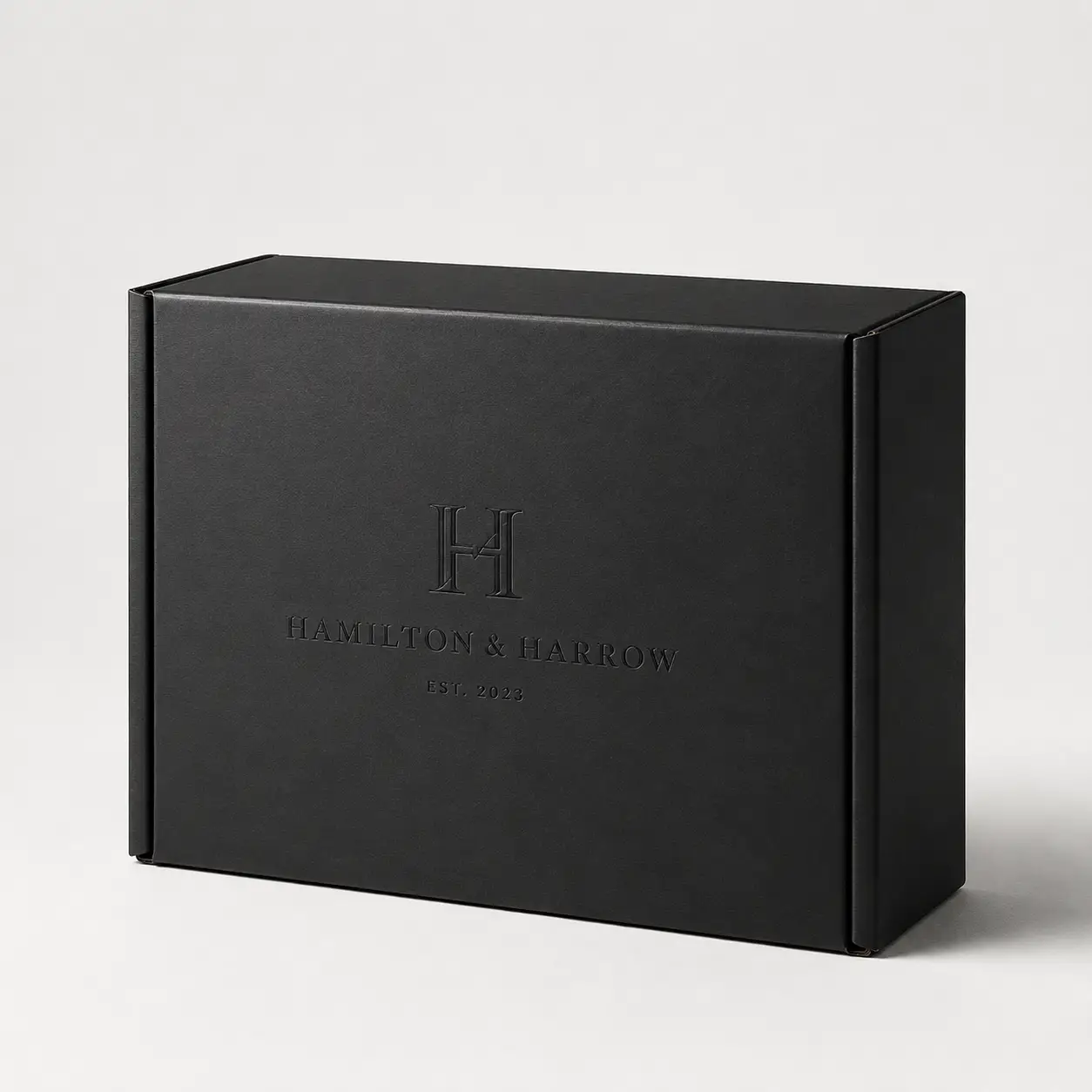 Matte black luxury mailer box with embossed Hamilton & Harrow Est. 2023 logo, elegant custom branded packaging design