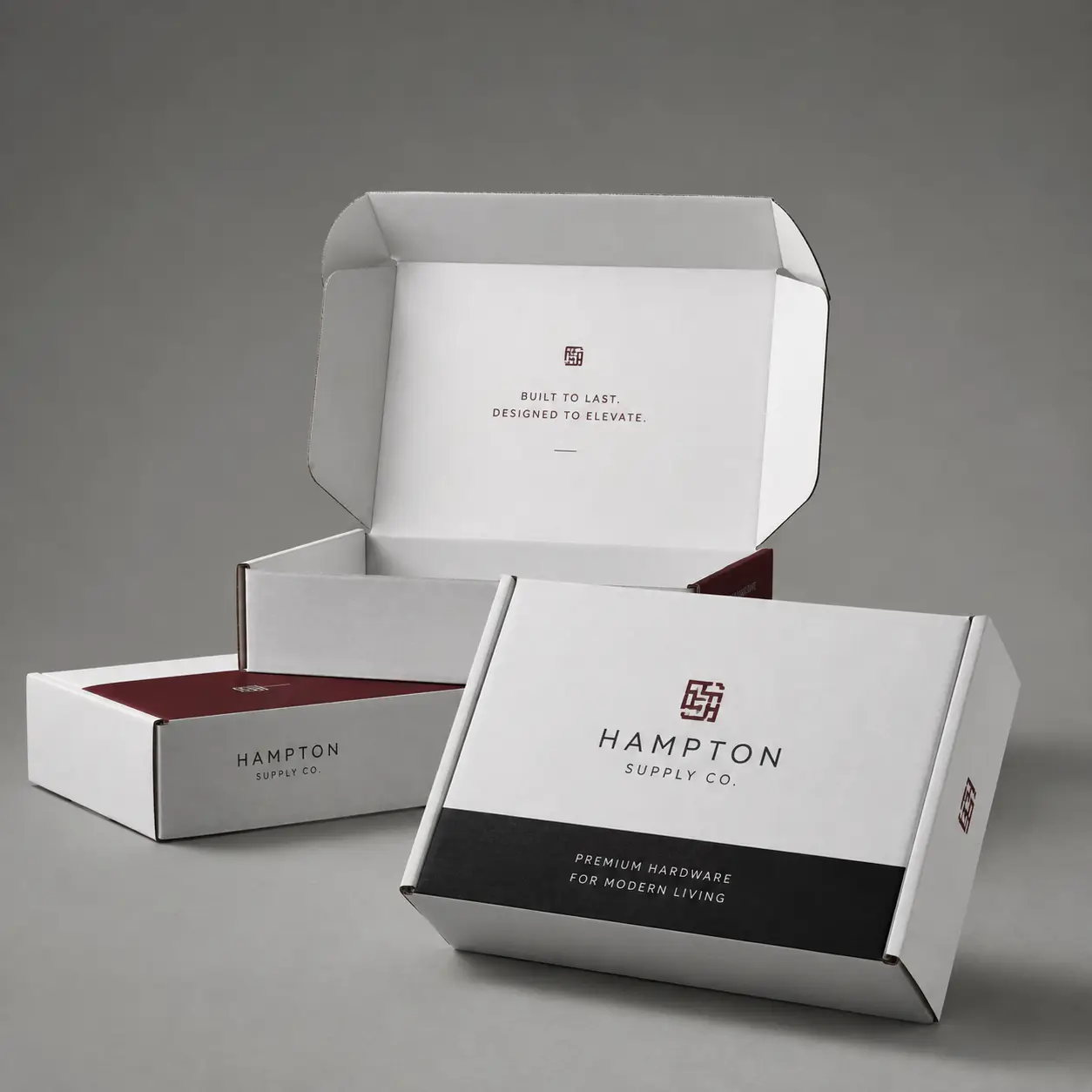 White Hampton Supply Co premium mailer boxes with burgundy logo, black band, open lid showing Built To Last tagline, elegant packaging design