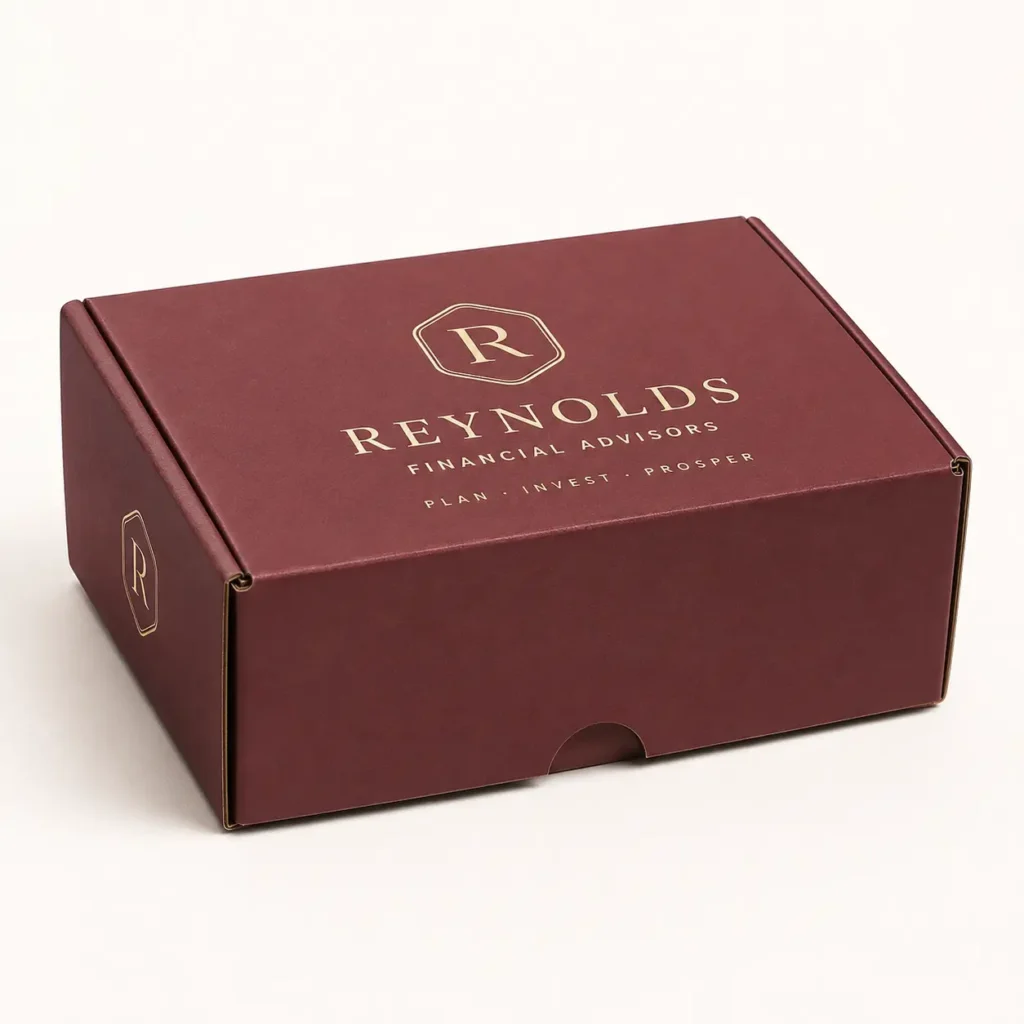Burgundy custom mailer box with gold foil Reynolds Financial Advisors logo, Plan Invest Prosper tagline, premium branded packaging