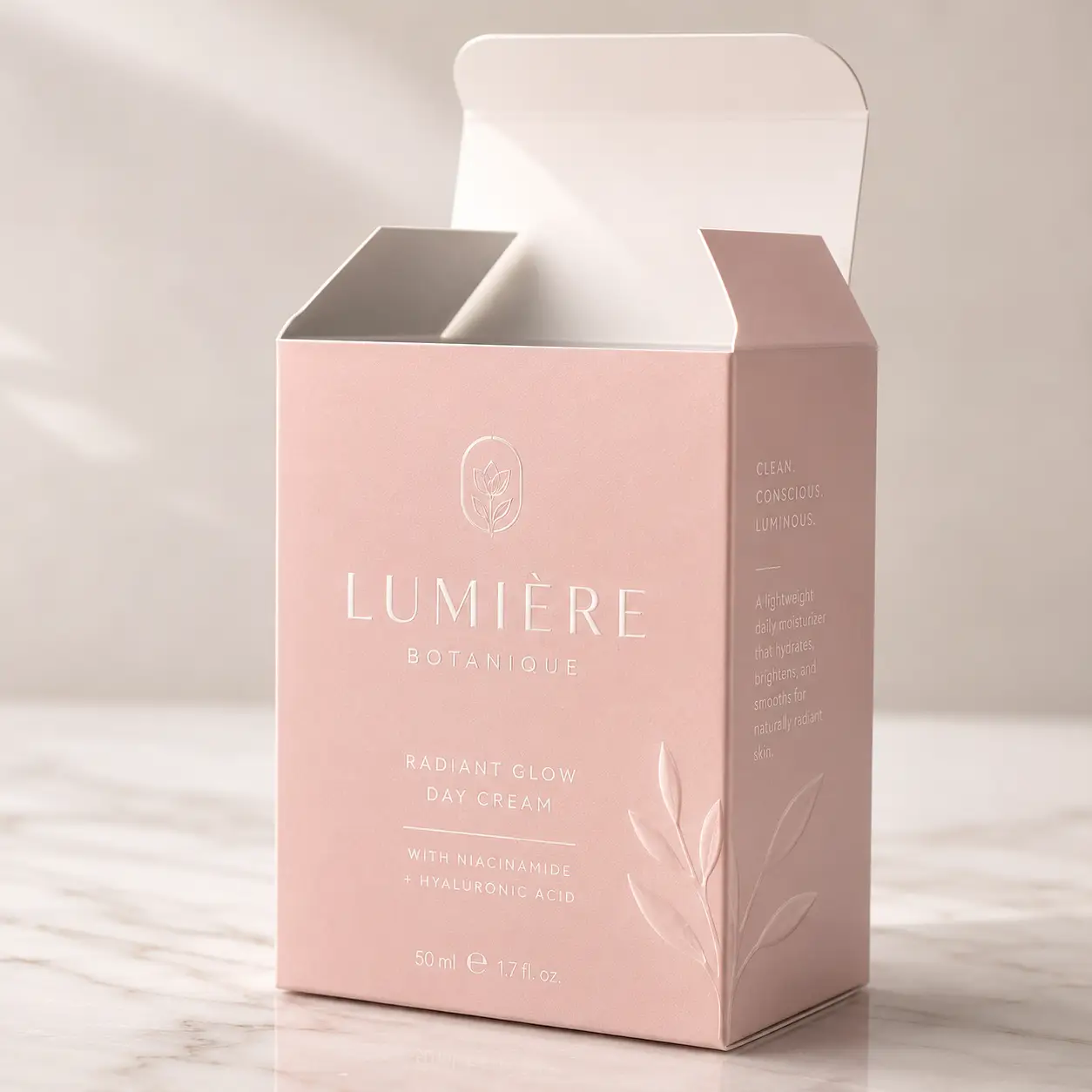 Pink luxury skincare box packaging for Lumière Botanique Radiant Glow Day Cream with embossed botanical design on marble surface