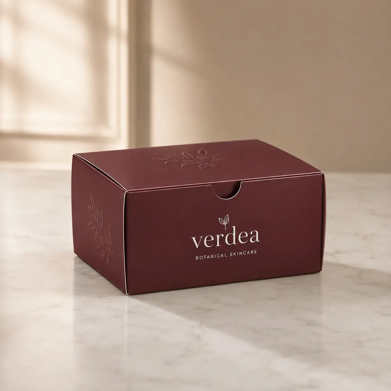 Verdea Botanical Skincare burgundy luxury gift box with embossed floral design on marble surface, premium custom packaging