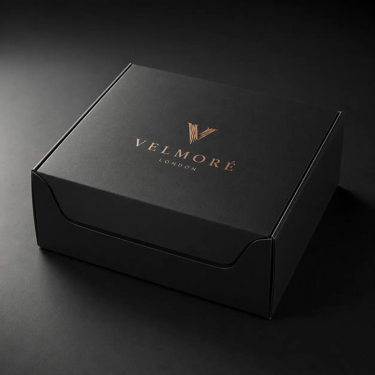Luxury black matte gift box with rose gold Velmoré London foil logo, premium custom packaging design on dark background