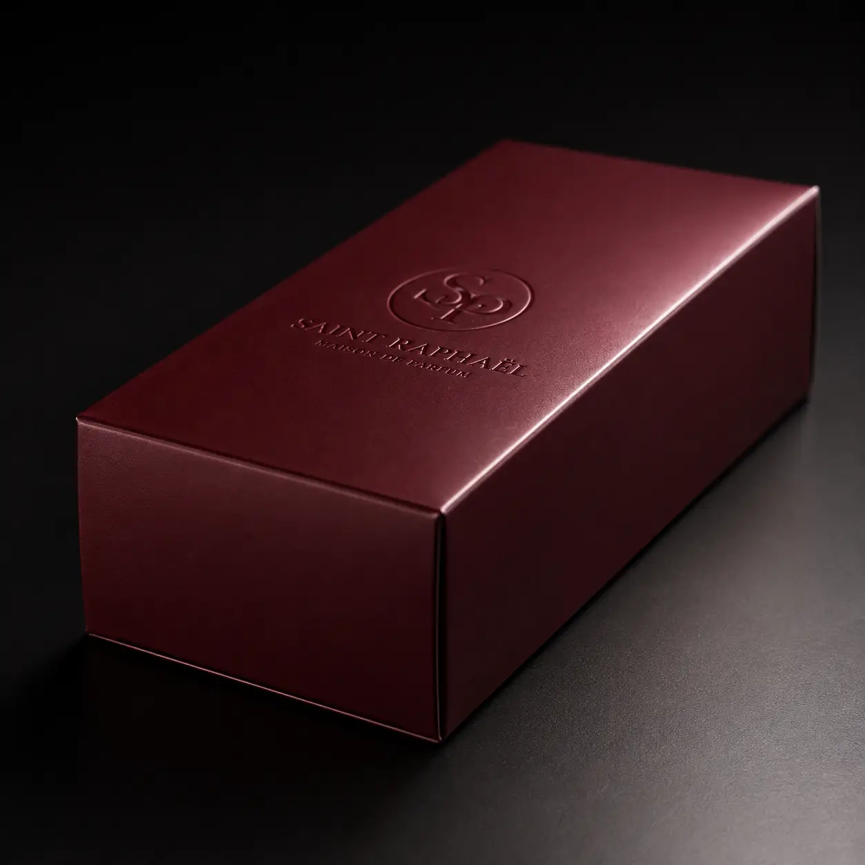 Luxury burgundy embossed gift box packaging for Saint Raphaël Maison de Parfum on dark background