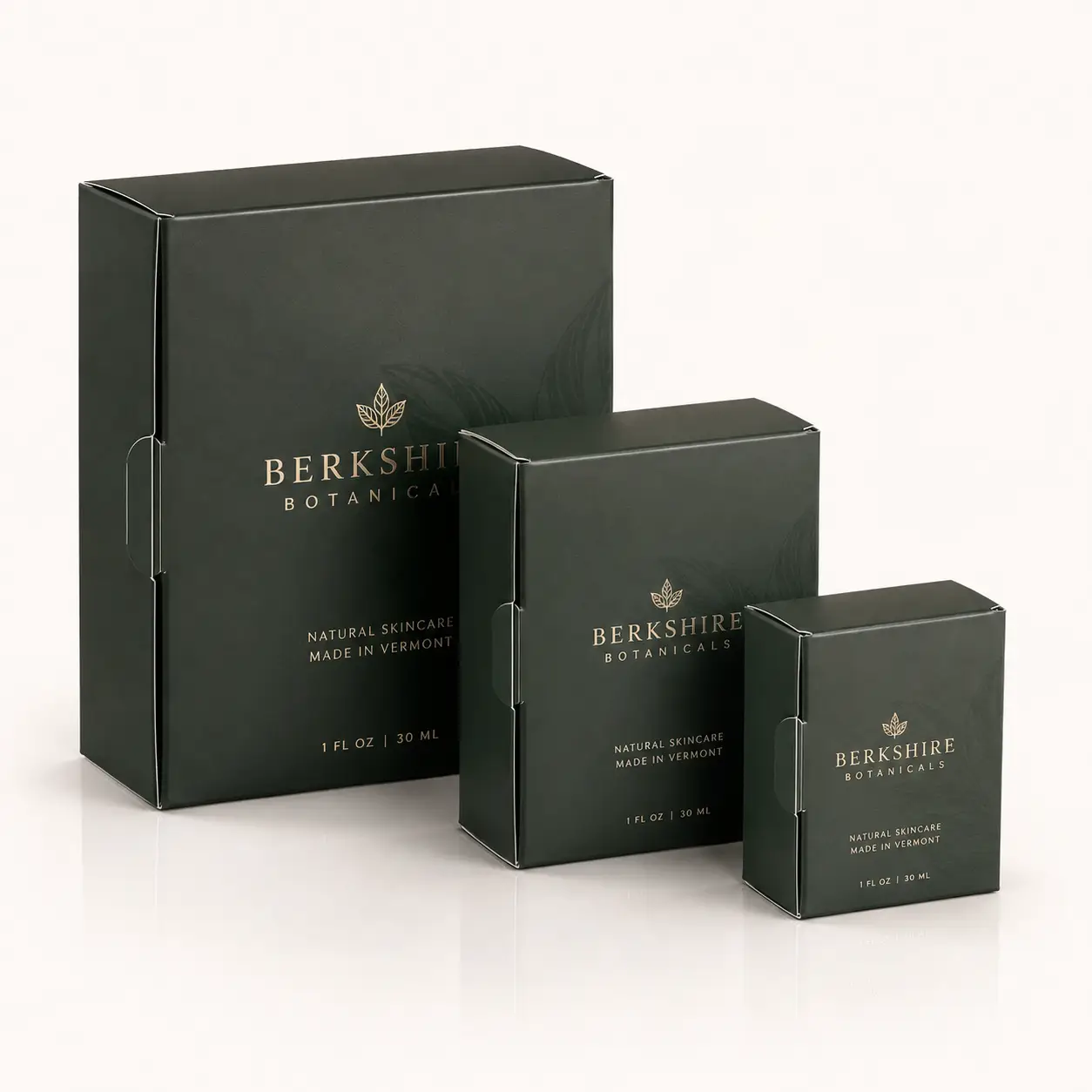 Three dark green luxury skincare boxes by Berkshire Botanicals with gold foil branding, graduated sizes, natural skincare packaging Vermont