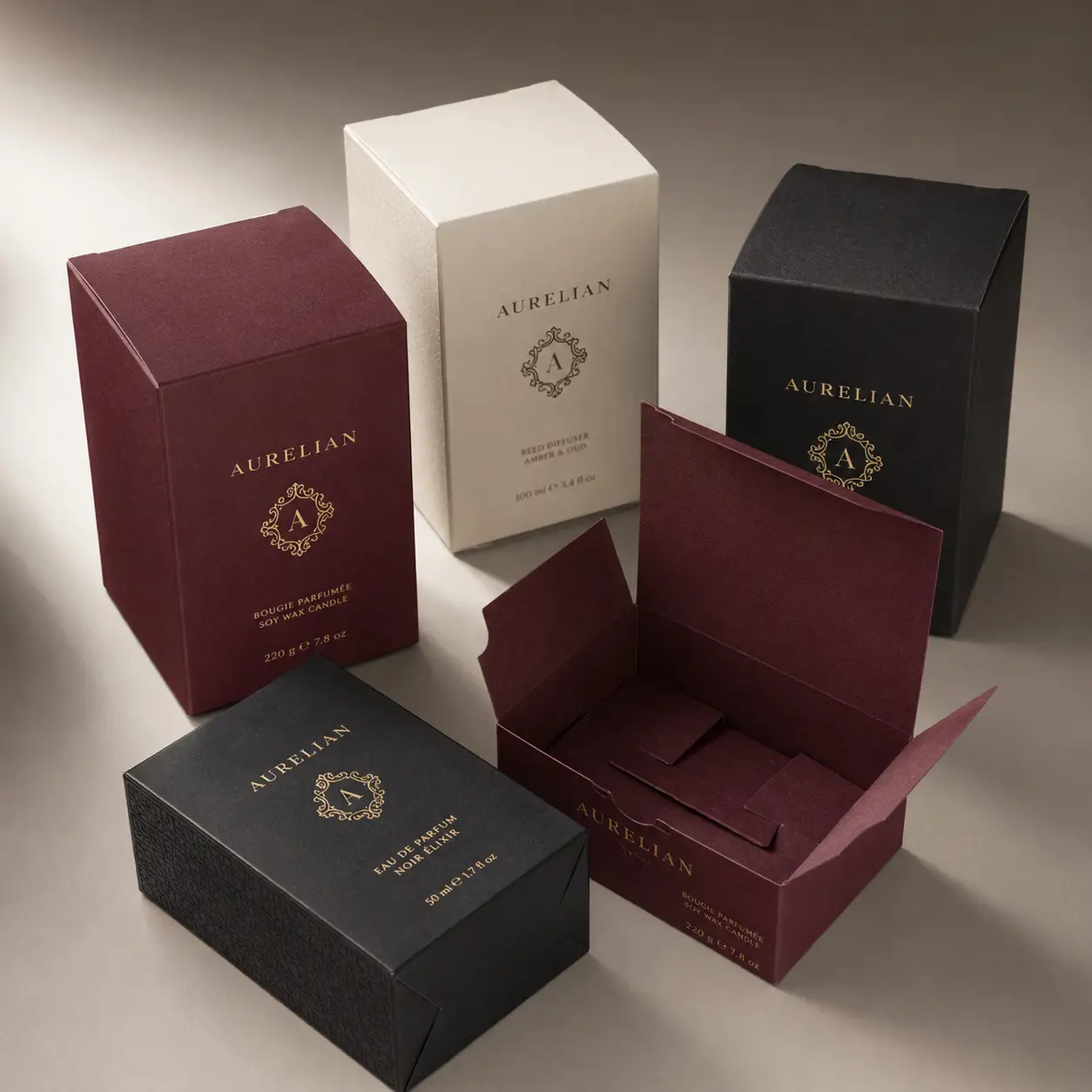 Luxury Aurelian brand packaging boxes in burgundy, black, and cream with gold foil logo, premium custom rigid box design