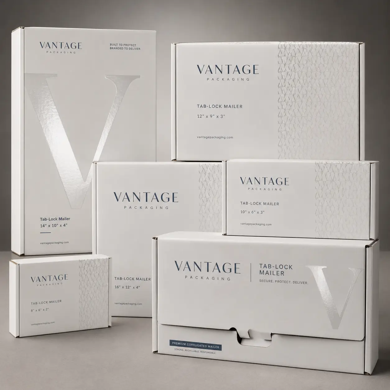 White Vantage Packaging corrugated tab-lock mailer boxes in multiple sizes arranged on gray surface, premium branded shipping solutions