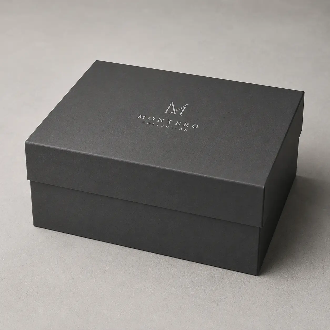 Dark gray luxury rigid gift box with silver Montero Collection logo, premium packaging design on neutral background