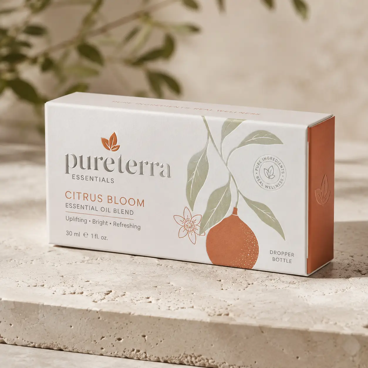 White PureTerra Essentials Citrus Bloom essential oil blend box with orange botanical illustration on stone surface