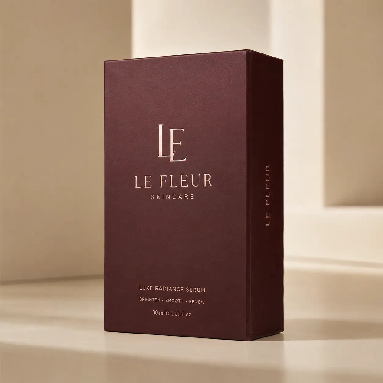 Luxury burgundy Le Fleur Skincare Luxe Radiance Serum box with rose gold foil branding on beige surface