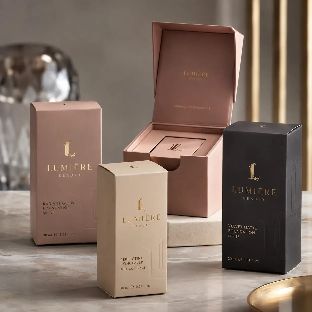 Lumière Beauty luxury cosmetic packaging boxes in blush pink, cream, and black displaying foundation SPF and concealer on marble surface