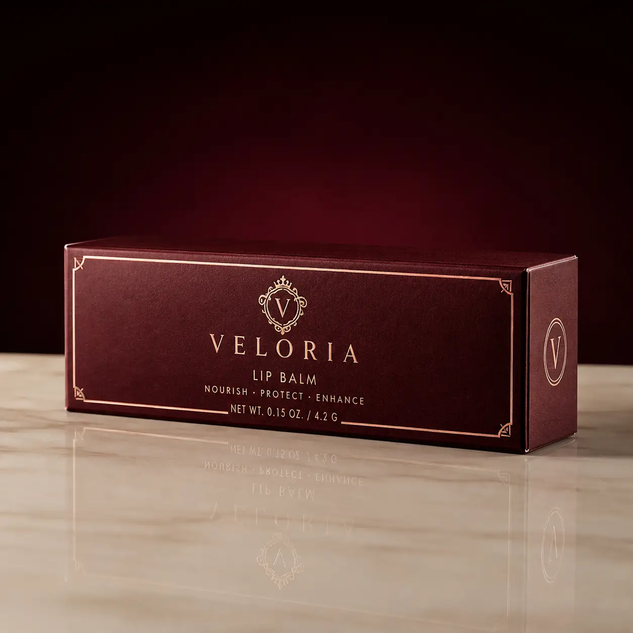 Veloria luxury lip balm packaging box in deep burgundy with gold foil branding on marble surface, elegant cosmetic box design
