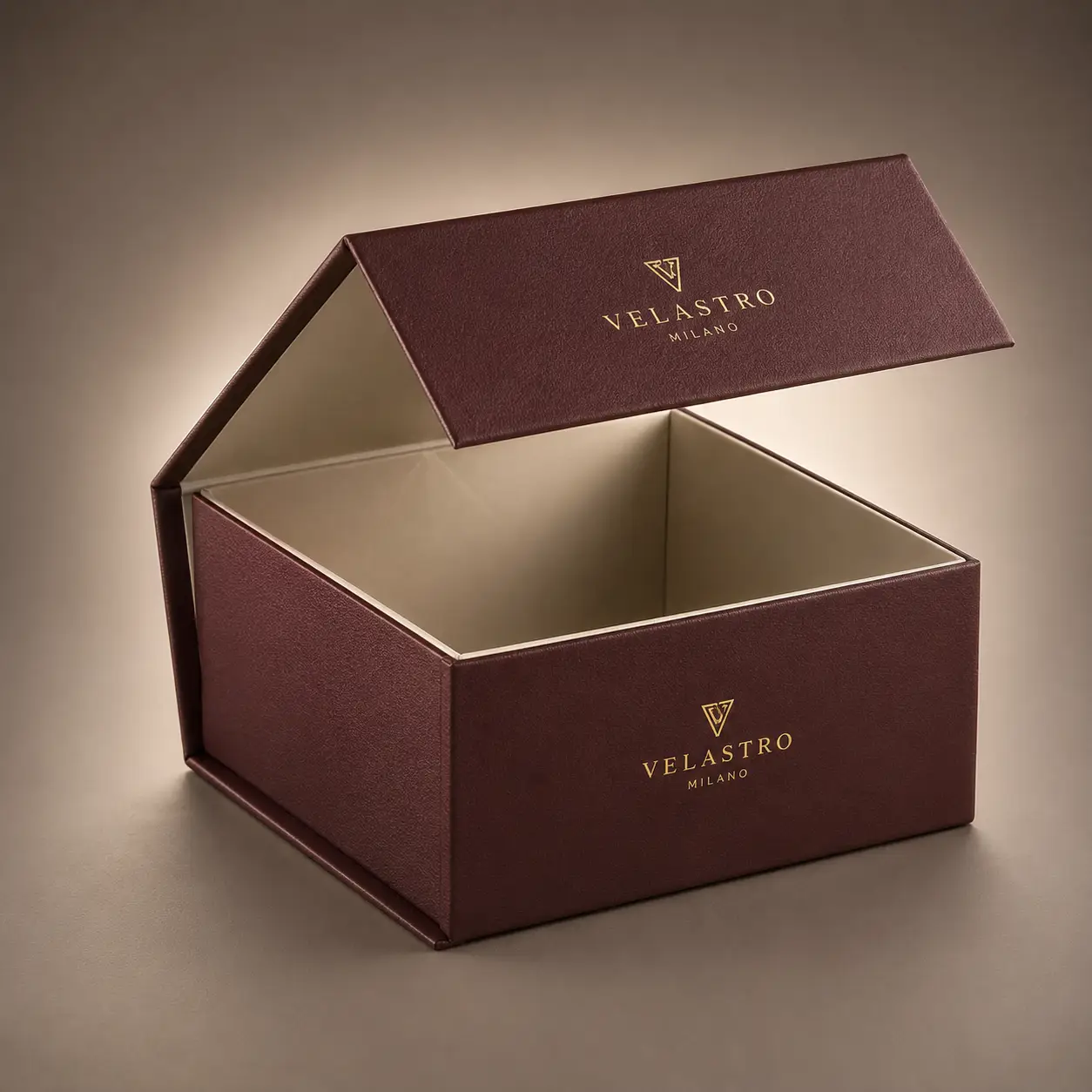 Luxury burgundy magnetic gift box with gold Velastro Milano logo, cream interior, open lid, premium rigid packaging design