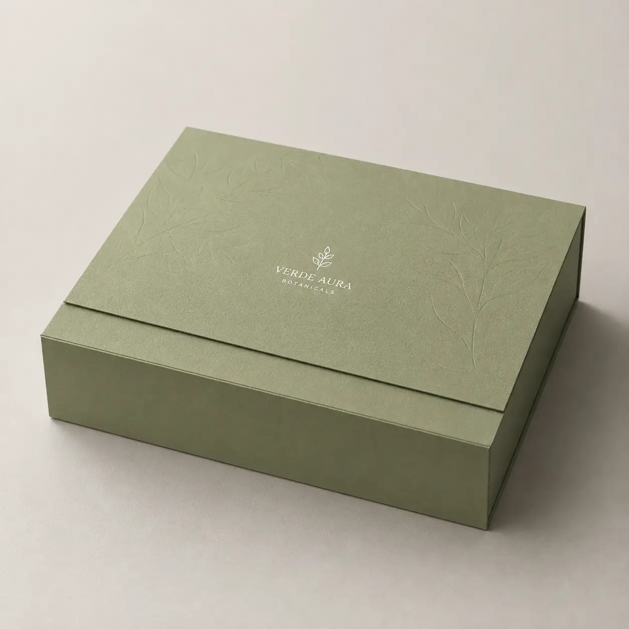 Sage green luxury gift box with embossed botanical leaf pattern and silver Verde Aura Botanicals logo, elegant custom packaging design