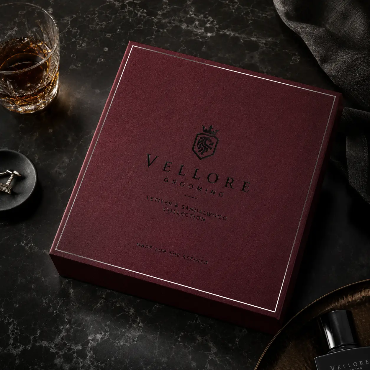 Vellore Grooming luxury burgundy gift box Vetiver Sandalwood Collection on dark marble with whiskey glass and cufflinks