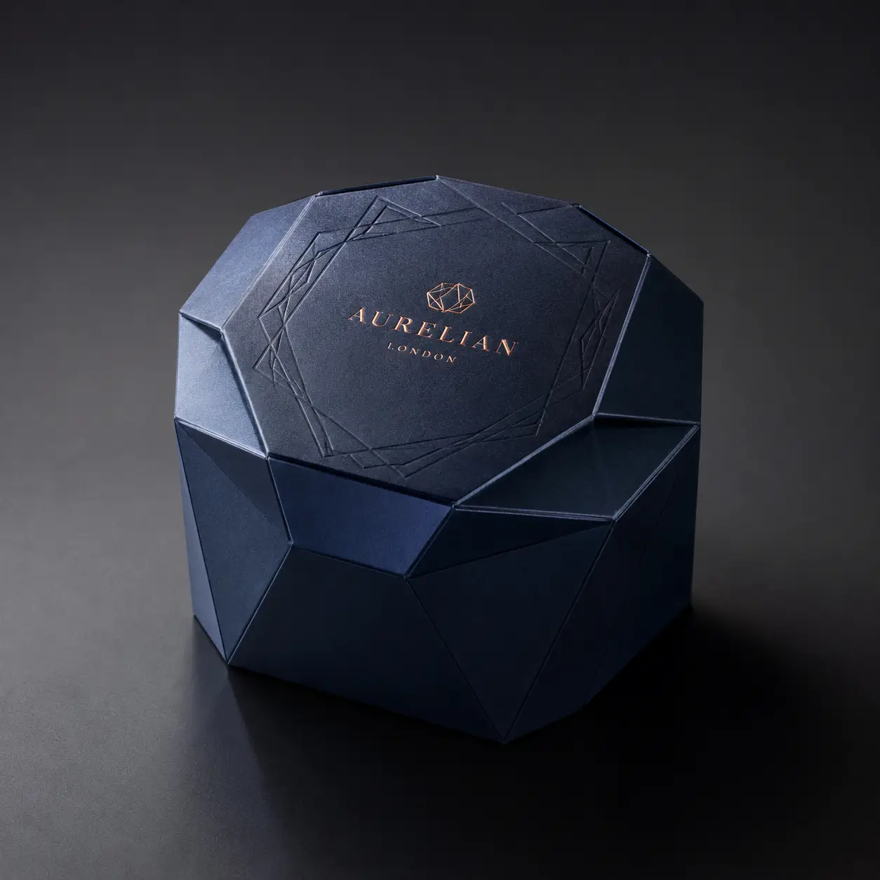 Navy blue luxury gem-cut rigid box with rose gold Aurelian London foil branding on dark background