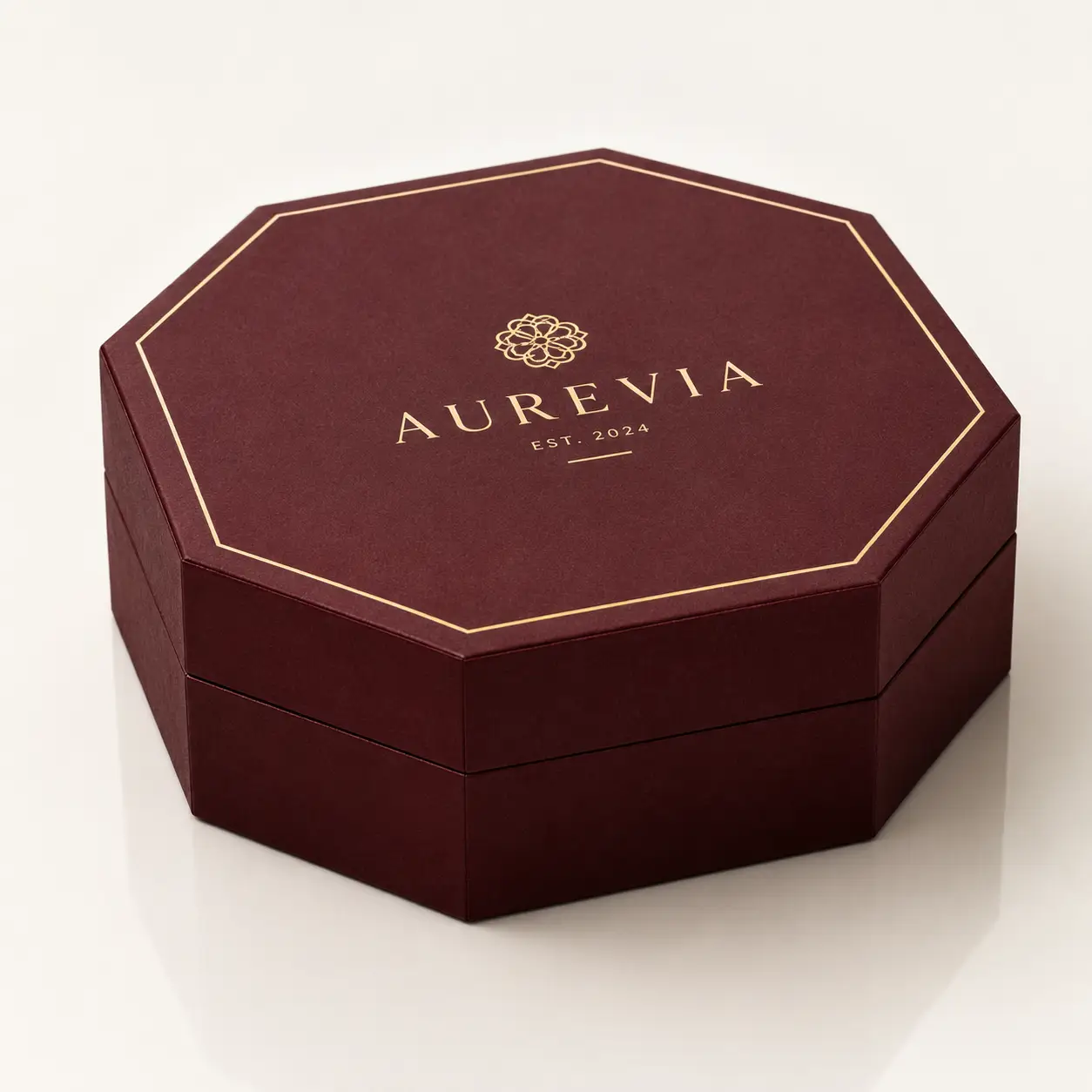 Aurevia Est. 2024 luxury octagonal gift box in deep burgundy with gold foil branding on white background