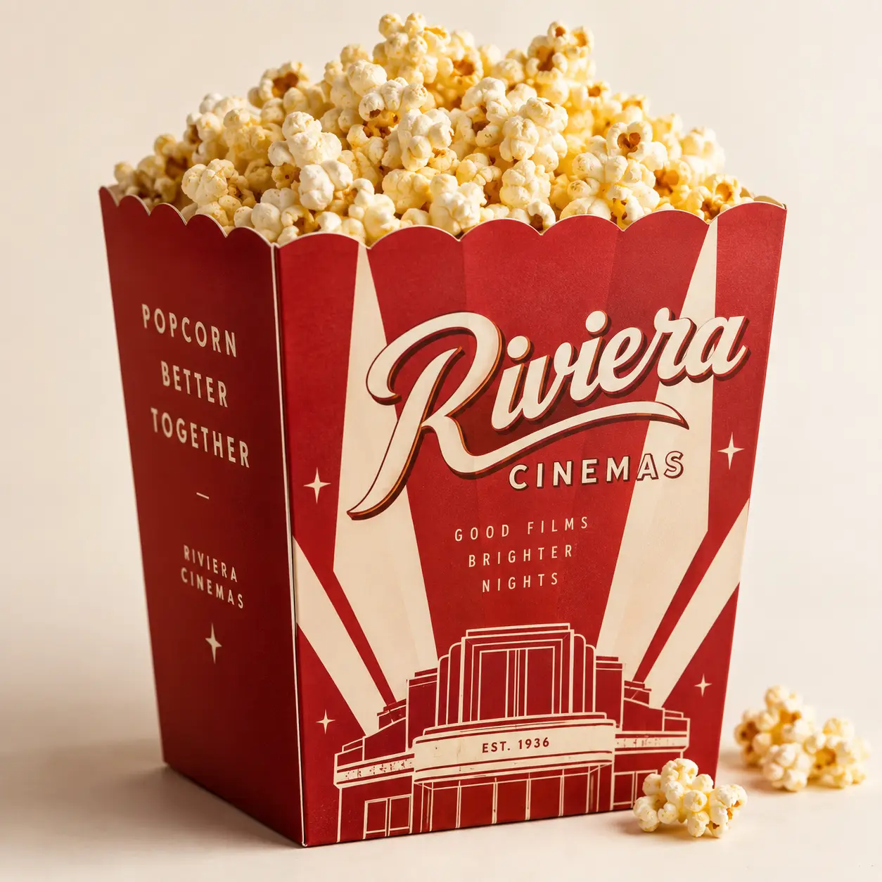 Red vintage Riviera Cinemas popcorn box packaging, EST. 1936, filled with fresh buttered popcorn, retro cinema branding design