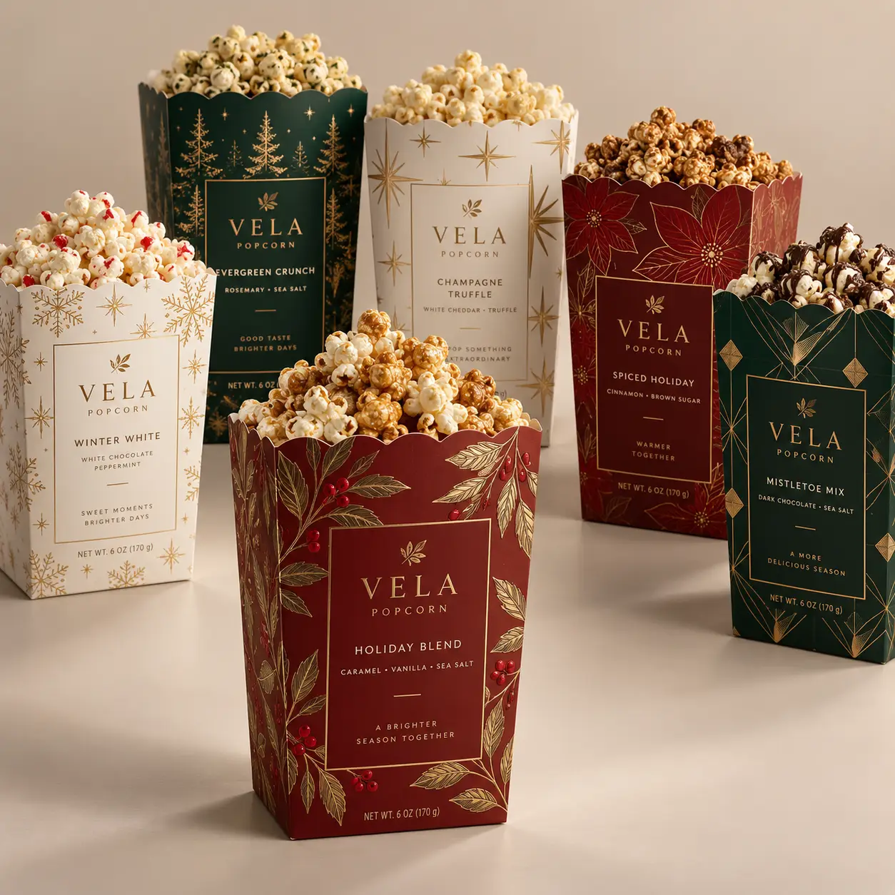 Six Vela Popcorn holiday gift boxes in red, green, and white with gold foil designs displaying festive flavors like Holiday Blend and Champagne Tru...