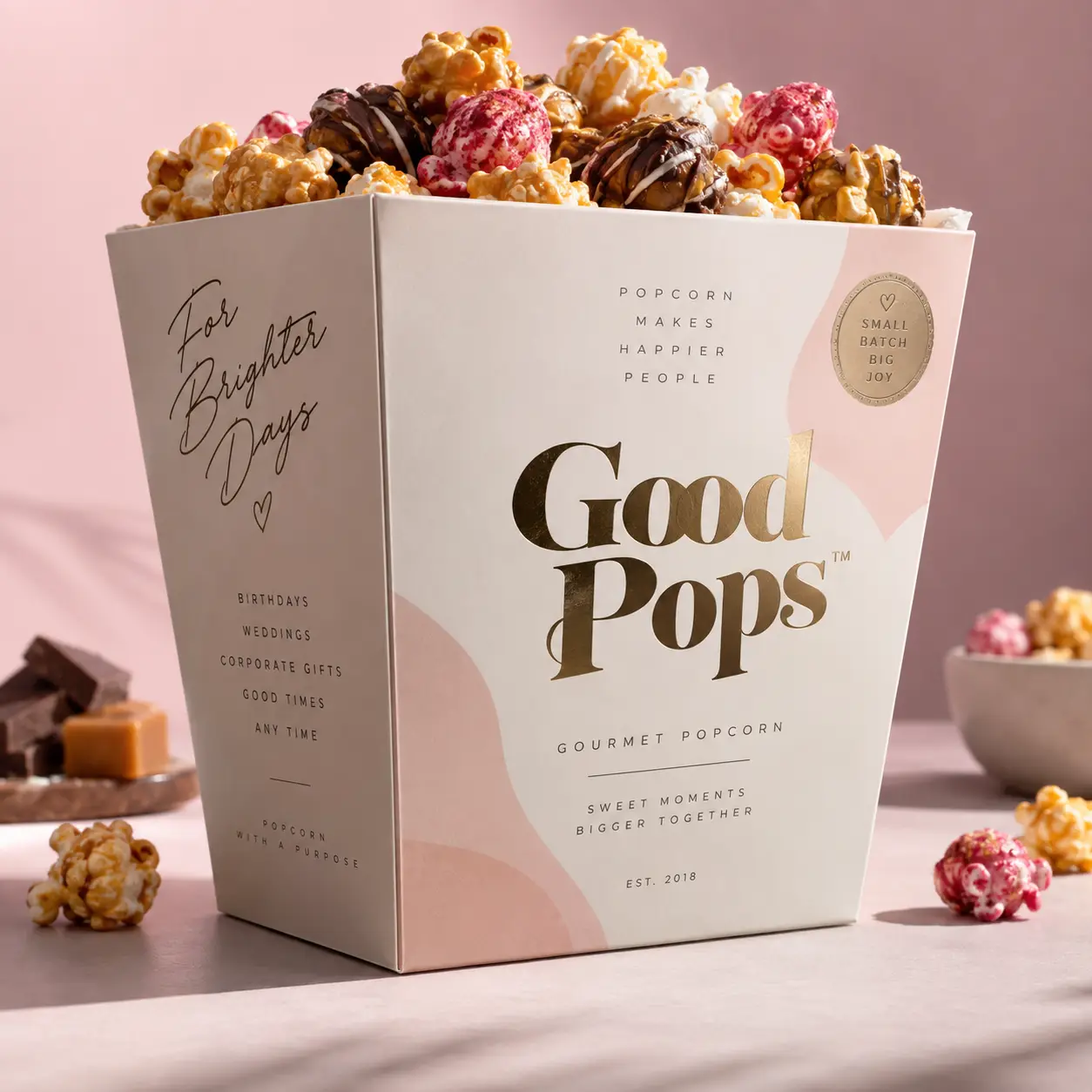 Good Pops gourmet popcorn gift box packaging in white and pink with gold branding, overflowing with caramel and chocolate popcorn