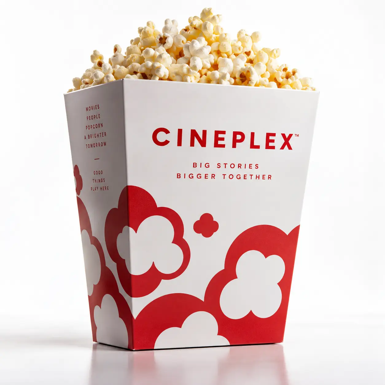 Cineplex branded popcorn box in red and white with bold typography and popcorn kernel graphics, overflowing with fresh buttered popcorn