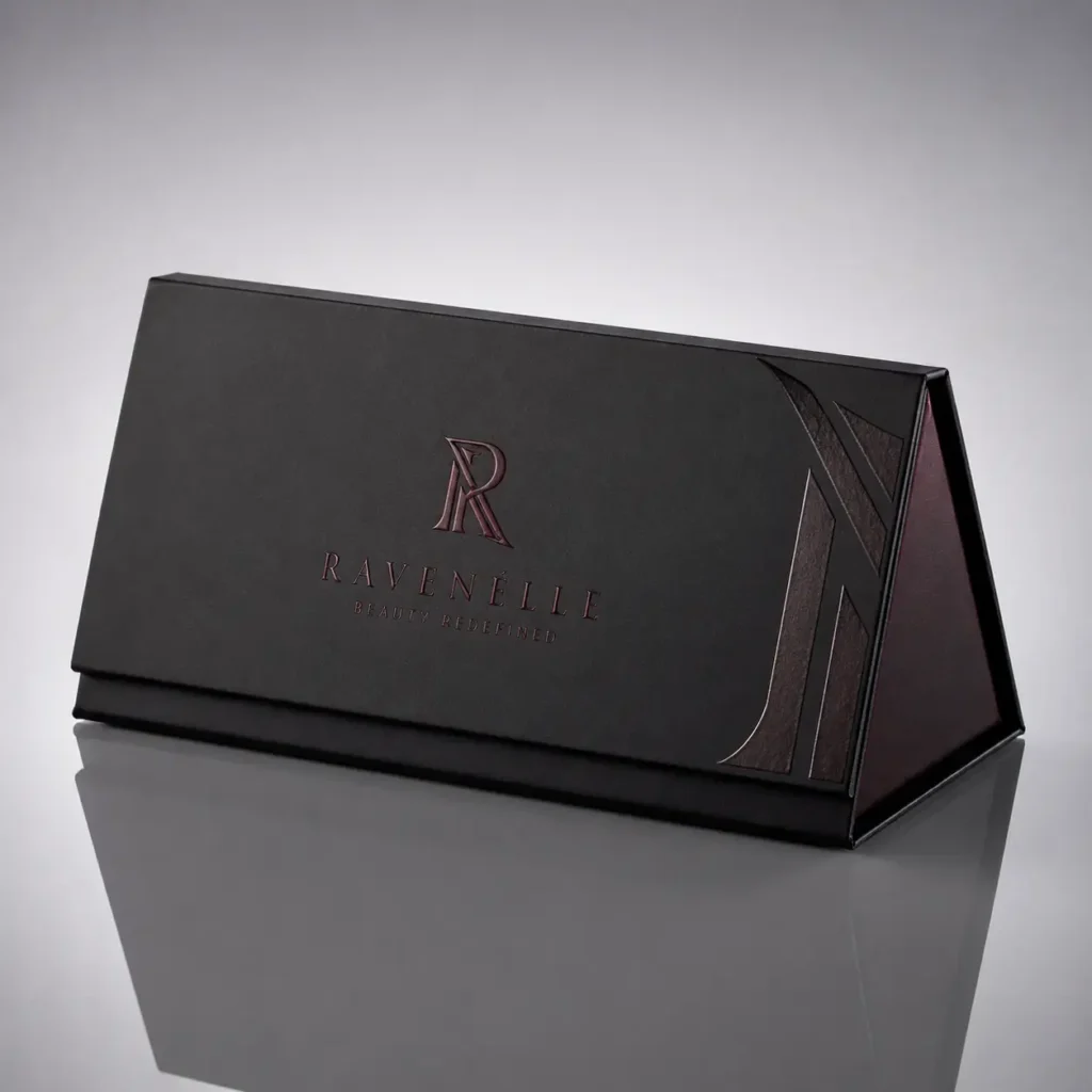 Ravenelle Beauty Redefned luxury black magnetic gift box with deep burgundy embossed logo on reflective surface
