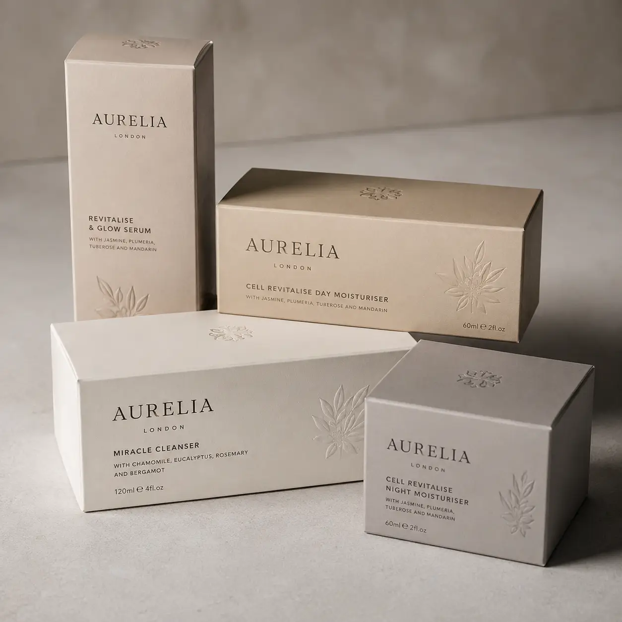 Aurelia London luxury skincare packaging set in beige and silver tones featuring cleanser, serums and moisturizers on grey surface