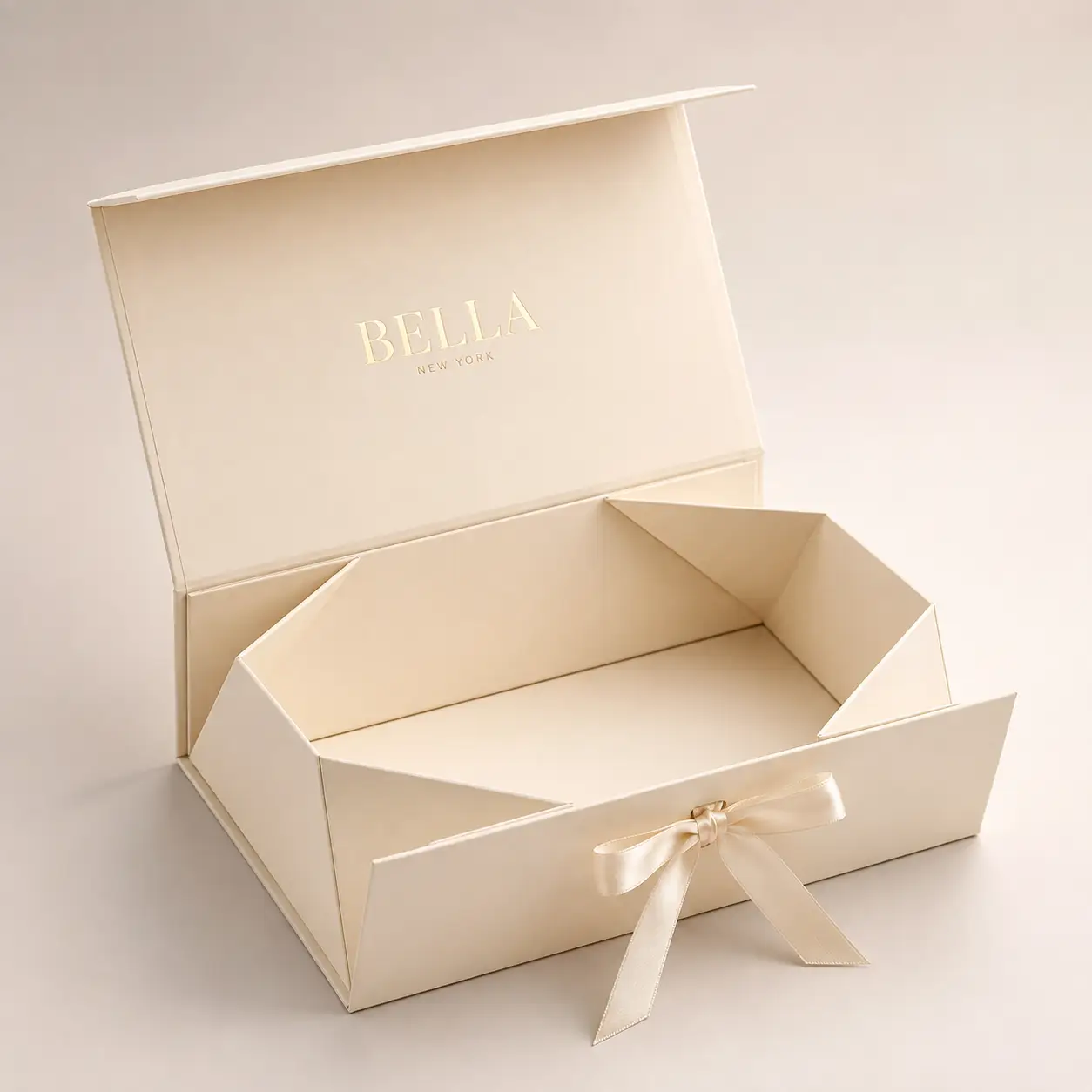 Luxury cream magnetic gift box with satin ribbon bow, gold foil Bella New York branding, elegant rigid folding packaging
