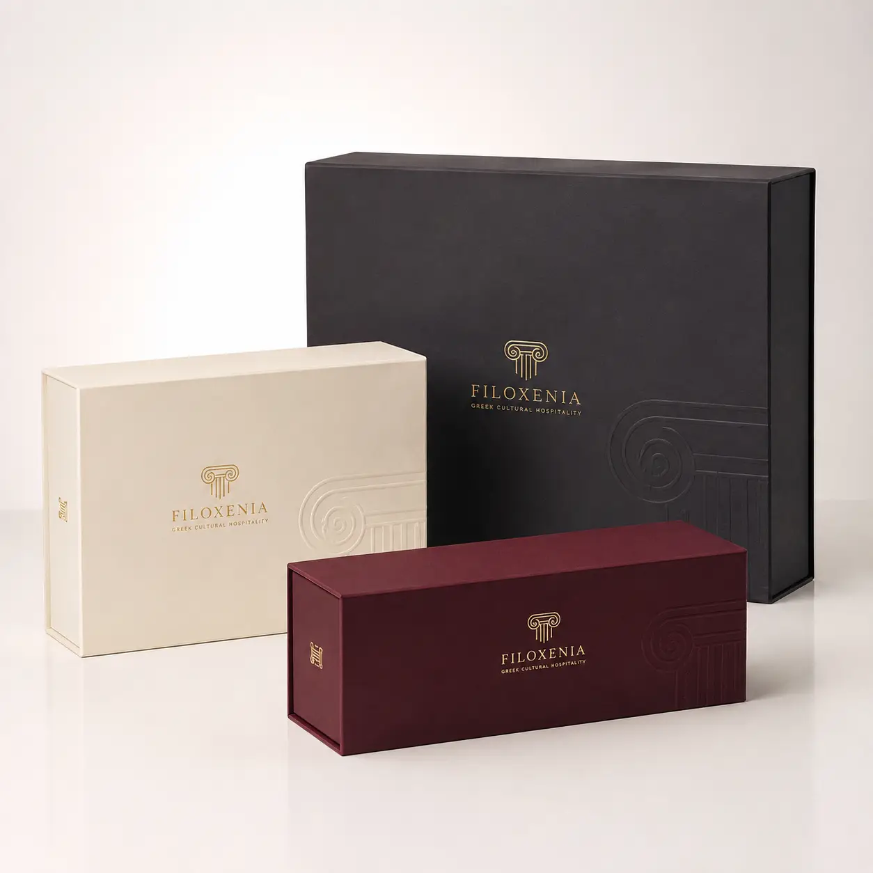 Filoxenia Greek luxury gift boxes in black, cream, and burgundy with gold foil logo, premium rigid packaging design