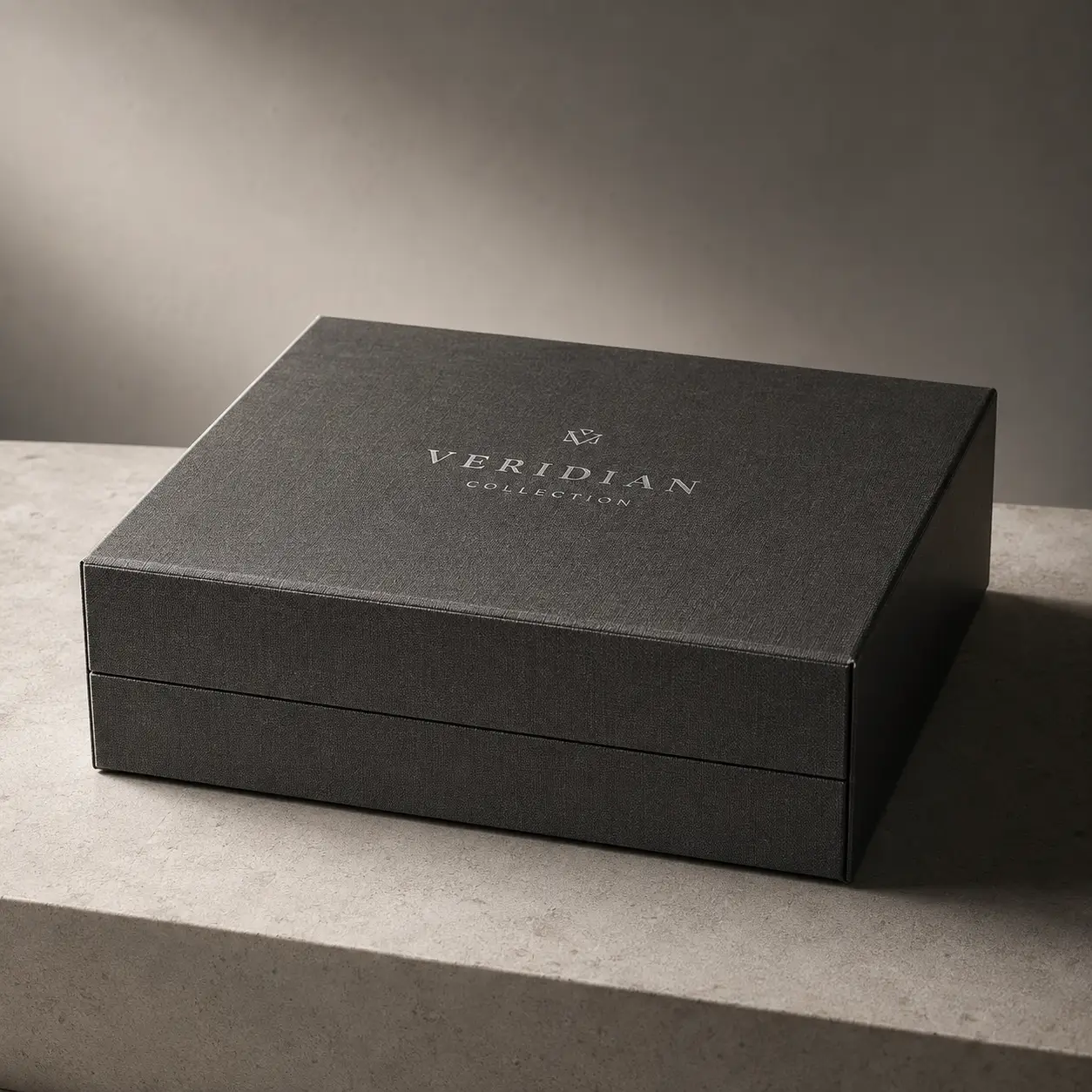 Dark charcoal luxury gift box with silver Veridian Collection logo on stone surface, premium rigid packaging design