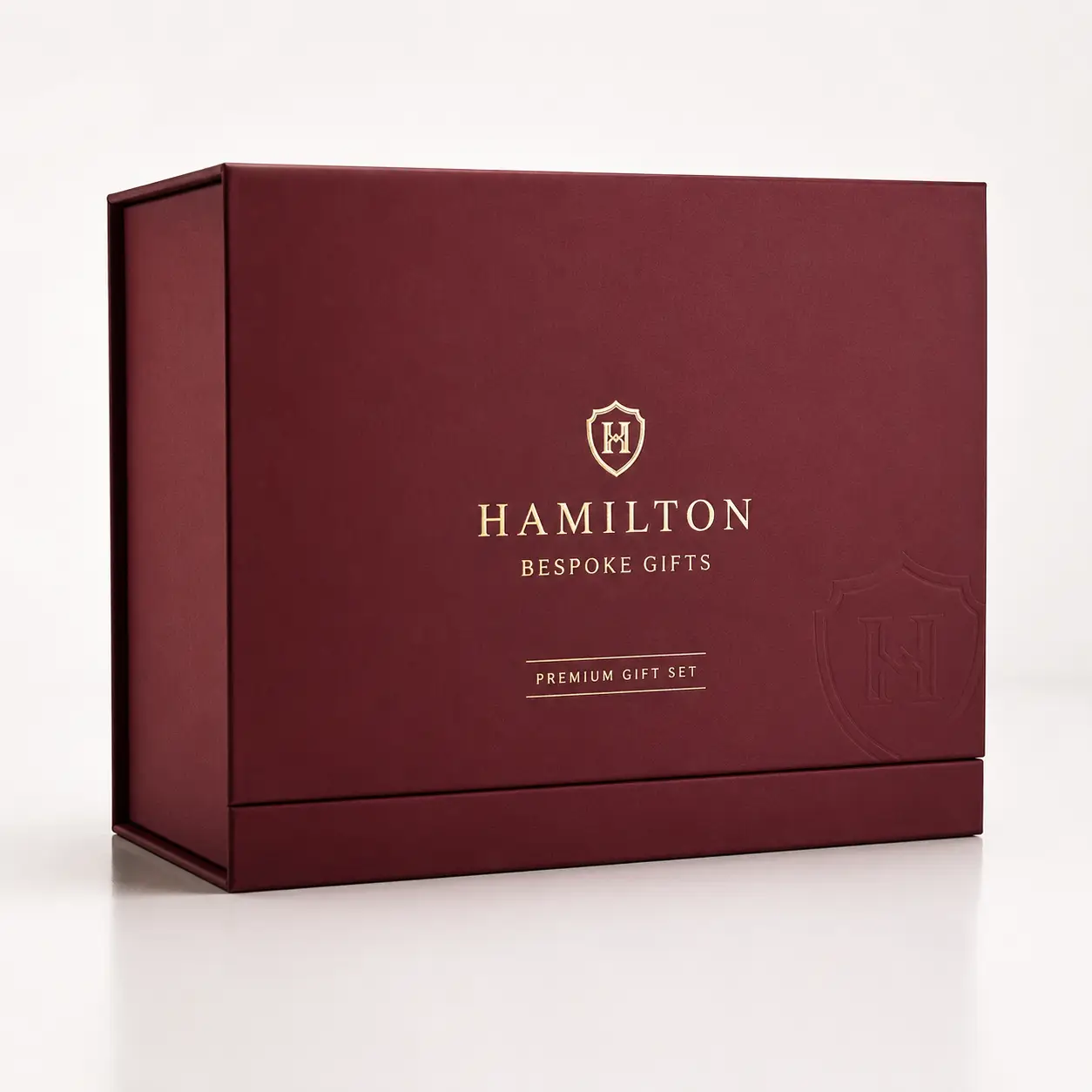 Luxury burgundy magnetic gift box with gold foil Hamilton Bespoke Gifts branding, premium rigid packaging with embossed crest