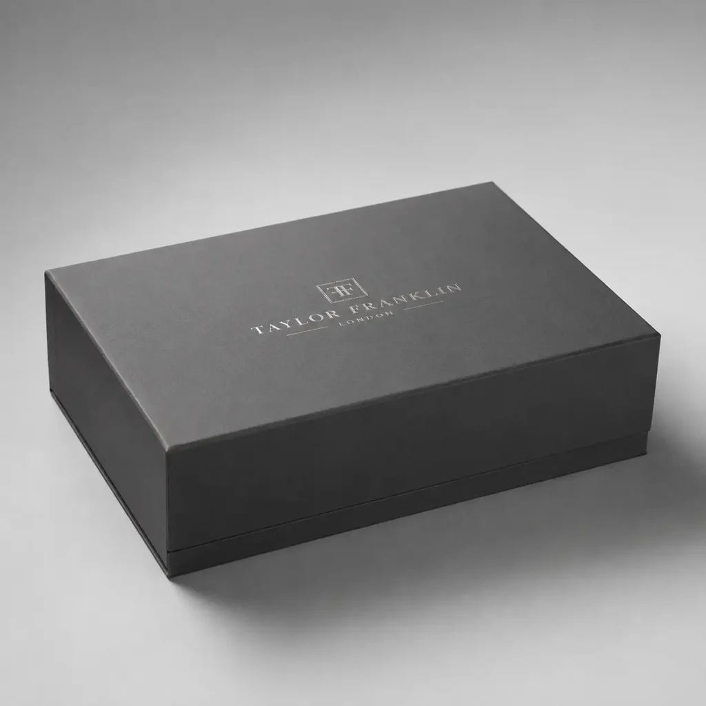 Luxury matte black magnetic gift box with silver foil Taylor Franklin London logo, premium rigid packaging on grey background