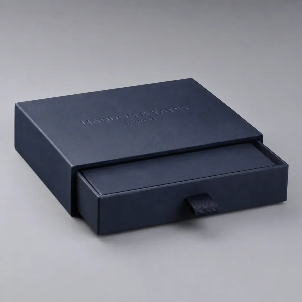 Navy blue luxury drawer gift box with embossed Haddon & Yates London branding and ribbon pull, premium rigid packaging