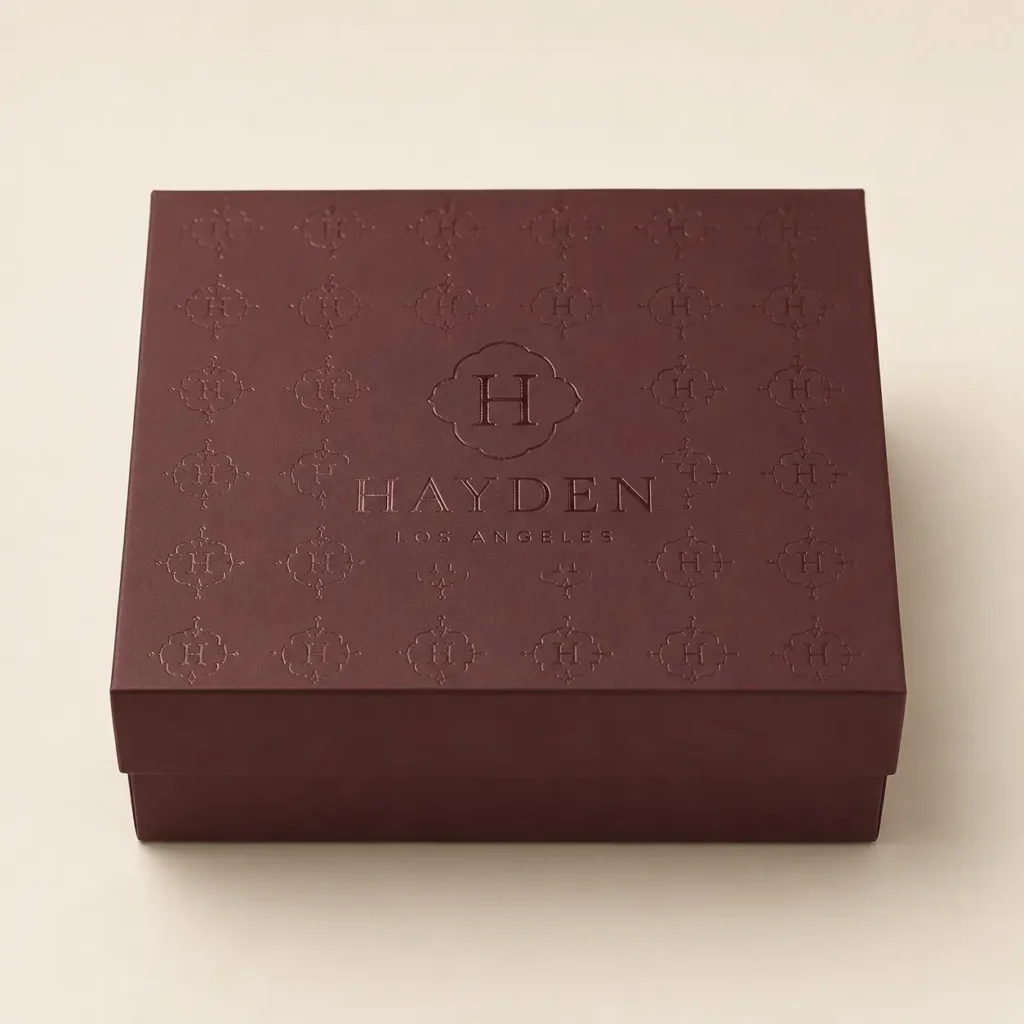 Luxury burgundy gift box with embossed Hayden Los Angeles monogram pattern, elegant branded packaging design by The Packaging Masters