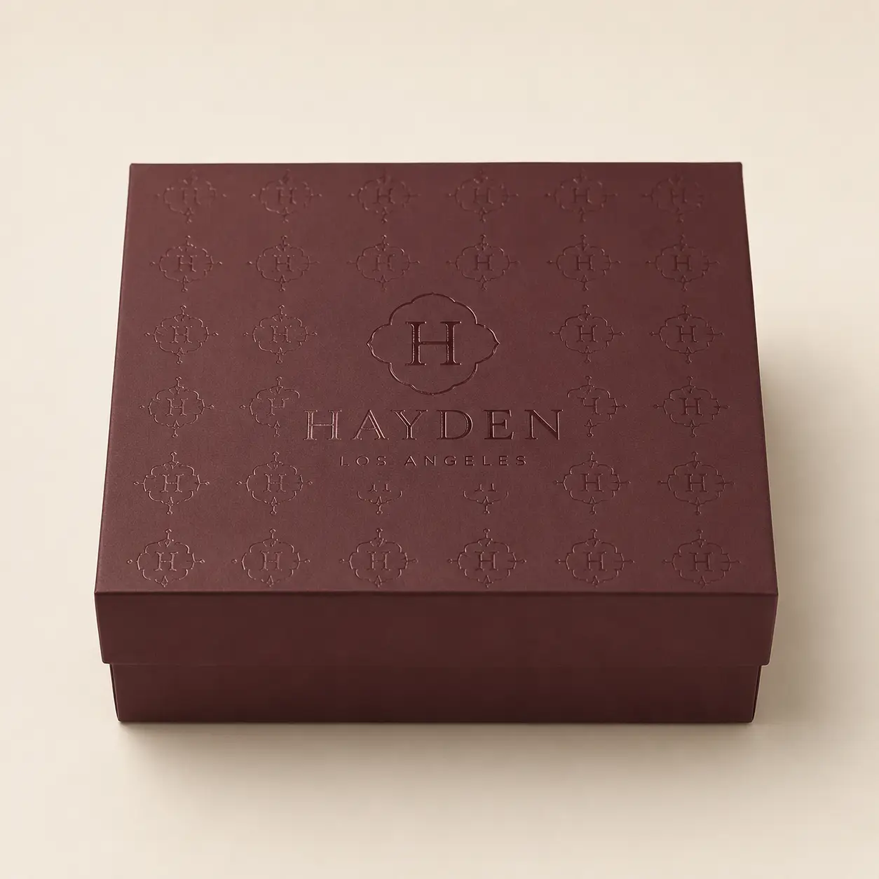 Luxury burgundy gift box with embossed Hayden Los Angeles monogram pattern, elegant branded packaging design by The Packaging Masters