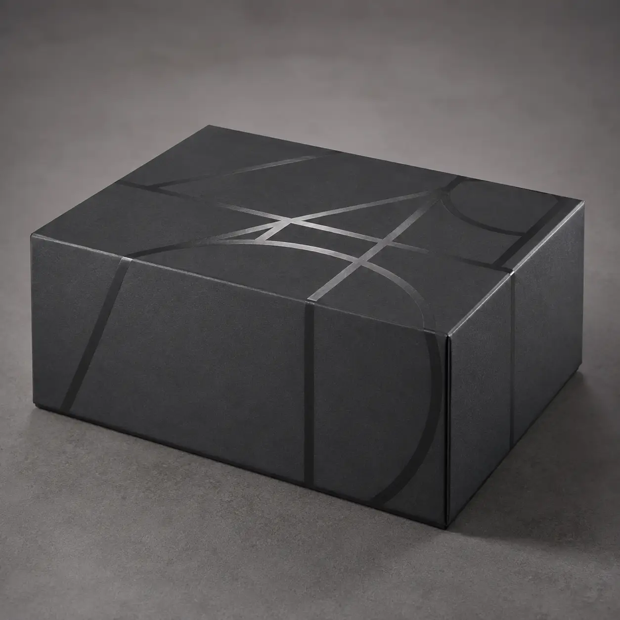 Matte black luxury gift box with glossy geometric line pattern, premium custom packaging design by The Packaging Masters
