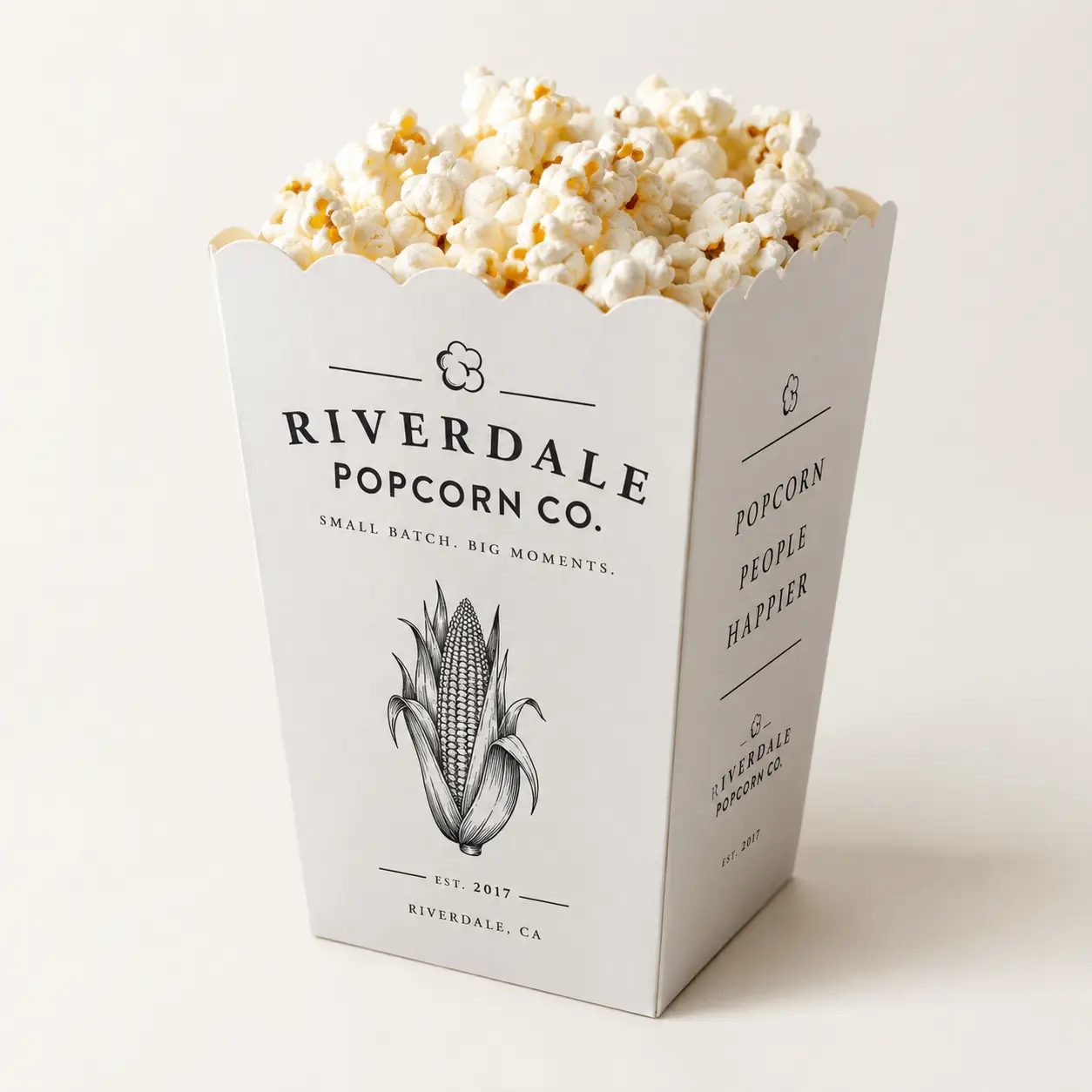 White popcorn box packaging design for Riverdale Popcorn Co, small batch brand, EST 2017, filled with fresh popcorn, minimalist style