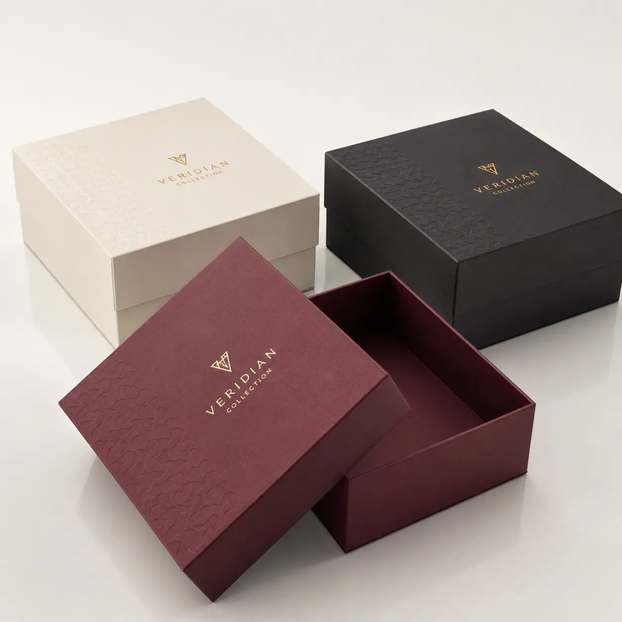 Three luxury Veridian Collection gift boxes in burgundy, cream, and black with gold foil logo and embossed texture packaging